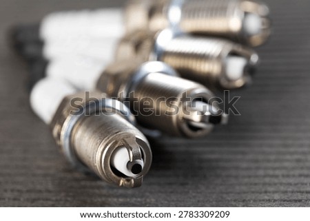 Close-up macro image of multiple spark plugs on textured dark surface, vital components of gasoline engine ignition system for vehicle performance