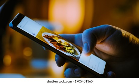 Close-up Macro: Person Holding And Using Smartphone, Browsing Through Pictures On Social Network Wall. Finger Scrolling Social Media App Feed: Travel, Animals, Food. Mock-up Application Design