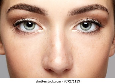 Closeup Macro Portrait Of Female Face. Human Woman Open Eyes With Day Beauty Makeup. Girl With Perfect Skin And Freckles.