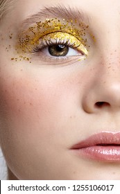 Closeup macro shot of  human female face. Woman with unusual glitter glitzy vogue face beauty makeup. Girl with perfect skin and yellow smoky eyes eye shadows