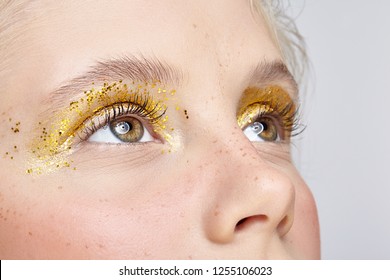 Closeup macro shot of  human female eye. Woman with unusual glitter glitzy vogue face beauty makeup. Girl with perfect skin and yellow smoky eyes eye shadows