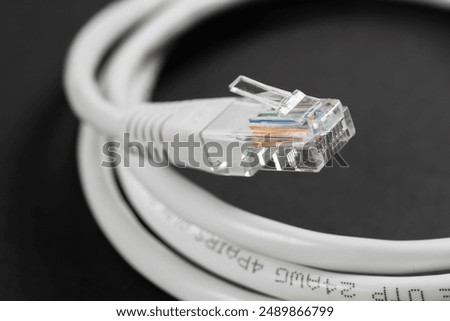 Close-up macro shot of a white RJ45 Ethernet cable on a dark table.