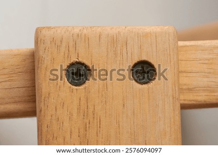 close-up macro view of countersunk black phillips head metal screws driven into the wood to flush with or below the surface, woodworking concept