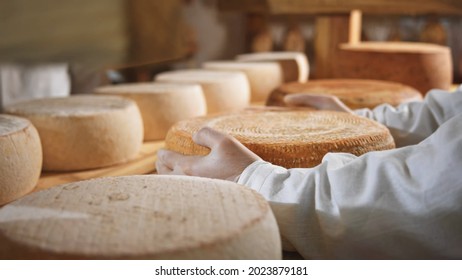 Close-up Macro View Of Farmer Hands Holding Big Fresh Exclusive Yellow Tasty Cheese Round On Wooden Table With Sunny Milky Farm On Background. Countryside Lifestyle. Eco Business. Healthy Nutrition.