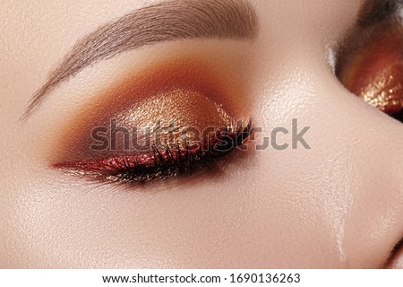 Closeup Macro of Woman Face with Gold glitter Eyes Make-up, bright red liner. Fashion Celebrate Makeup, Glowy Clean Skin, perfect Shapes of Brows. Shiny Simmer and metalic eye shadows
