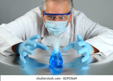 Closeup Of A Mad Scientist As He Observes A Chemical Reaction In His Laboratory. Man Is Partially Hidden Behind A Glass Beaker That Is Bubbling Over And Smoking.