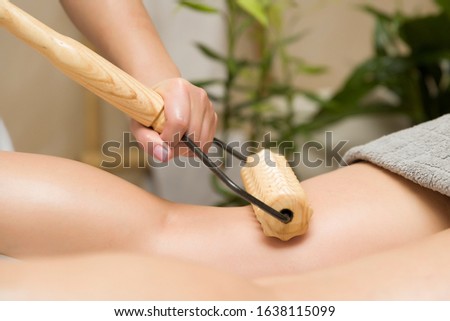 Closeup of the maderotherapy anti-cellulite leg massage with wooden roller massager