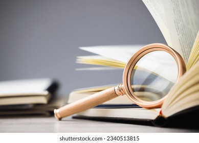 Closeup magnifying glass lean on the page of the opened book, research information, glossary, education concept - Powered by Shutterstock