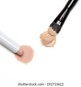 Close-up Of Makeup Concealer Pencil And Foundation With Brush On White Background