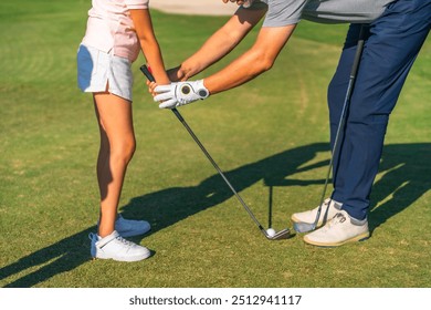 Close-up of a male adult instructor teaching golf lessons to a girl - Powered by Shutterstock