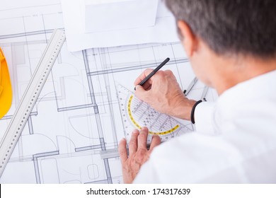 Close-up Of Male Architect Drawing Blueprint In Office