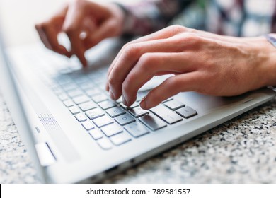 Closeup of male arm, typing on laptop, job search, job online, in a cafe with a laptop, fingers press the button