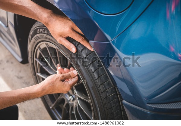 Closeup male automotive technician removing tire\
valve nitrogen cap for tire inflation service at garage or gas\
station. Car annual maintenance and repair concept. Safety road\
trip and travel theme.