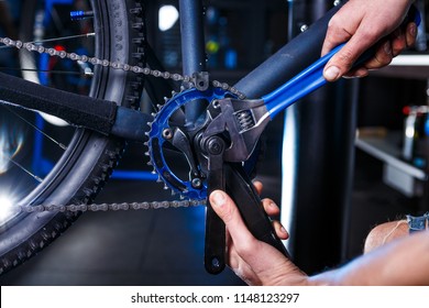 A close-up of a male bicycle mechanic's hand in the workshop uses a screwdriver tool to adjust and repair the bicycle crank assembly, the front bike stars in the bicycle store - Powered by Shutterstock