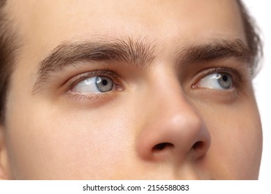 Closeup male blue eyes of young handsome man isolated on white studio background. Concept of men's health, vision, self-care, medicine and cosmetics. Natural beauty