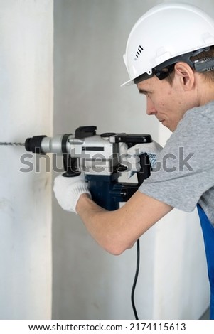Close-up of Male Builder Using a Puncher at Construction Site. Repair Home and House Renovation Service