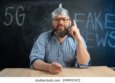 close-up of a male conspiracy theorist in a protective foil cap and glasses debunks myths. Conspiracy theory and the harm of the 5g network. Mobile killer. The schizophrenic works. Copy space.