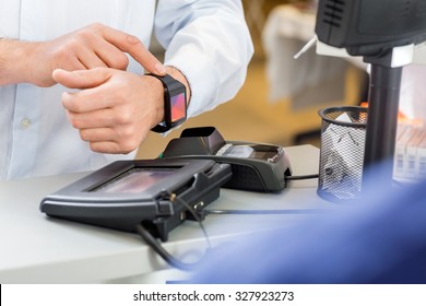 Closeup of male customer paying through smartwatch at counter in pharmacy - Powered by Shutterstock