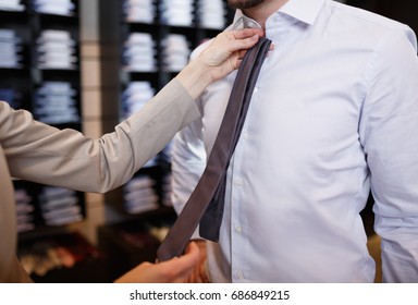 Close-up Of Male Customer At Shopping Mall Put On Business Clothes, Shop Assistant Helping Client To Choose Tie