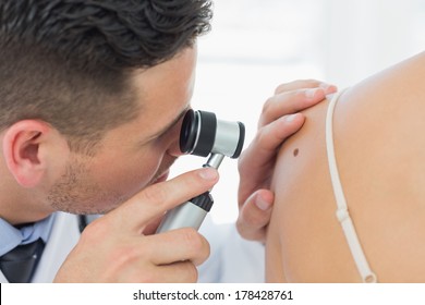 Closeup Of Male Dermatologist Checking Mole On Woman In Clinic