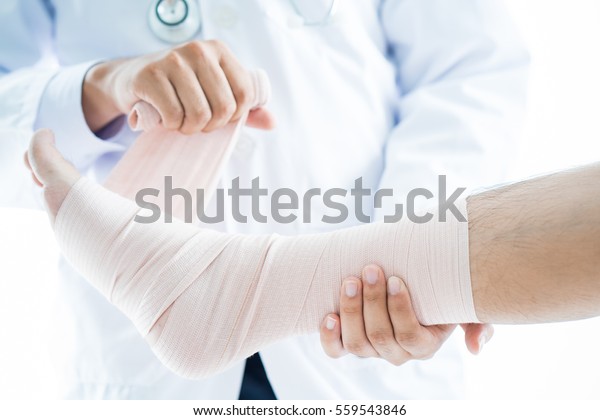 Close-up of male doctor bandaging foot of patient\
at doctor\'s office.