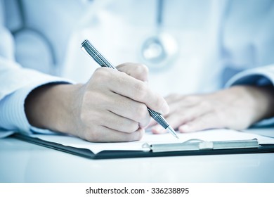 Close-up Of Male Doctor Filling The Medical Form