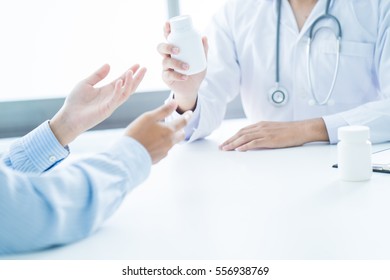Close-up of male doctor giving jar of pills to patient.