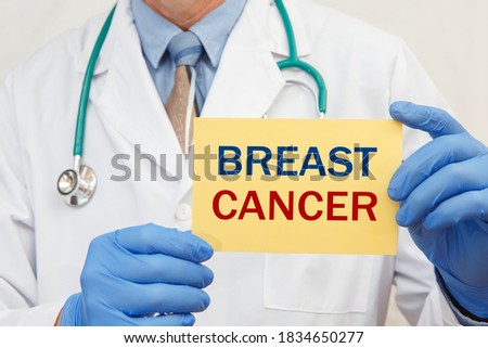 Close-up of a male doctor in gloves holding a sign with the text Breast cancer.