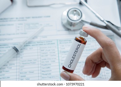 Closeup Of Male Doctor Hand Holds A Small Bottle Of Drug For Cholesterol Disease With Medical Record Form In The Hospital