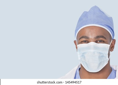 Close-up Of A Male Doctor Wearing Facemask Over Light Blue Background