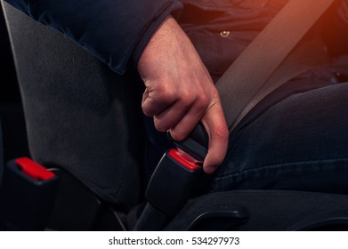 Closeup of male driver in casual cloth fastening seat belt in car. Auto safety concept.