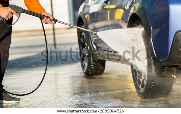 Closeup of male driver\
washing his car with contactless high pressure water jet in self\
service car wash.