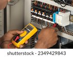 Close-up Of Male Electrician Checking Fuse Box With Multimeter