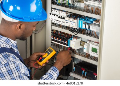 Close-up Of Male Electrician Checking Fuse Box With Multimeter