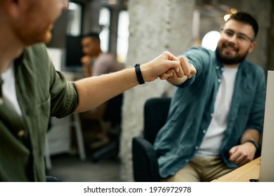 Close-up of male entrepreneurs congratulating each other and fist bumping while working in the office.  - Powered by Shutterstock