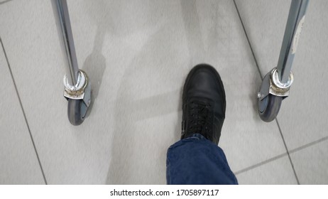 Close-up of male feet walking with shopping cart. Man buyer carrying purchases to parked car after shopping in supermarket.