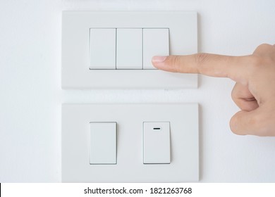 Closeup Male Finger Is Turn On Or Off On Light Switch On White Wall At Home. Energy Saving, Power, Electrical And Lifestyle Concepts