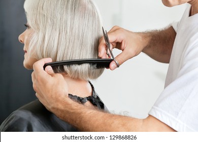 Closeup of male hairstylist measuring hair length before haircut in parlor - Powered by Shutterstock