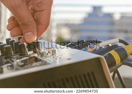 closeup of male hand controlling audio input volume on outdoor music mixing panel, music concept, copy space.