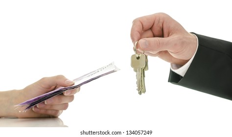 Closeup Of Male Hand Giving House Keys To A Woman In Exchange For Money. Concept Of Final Step In Purchasing A New House.