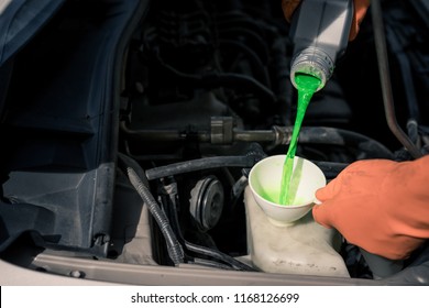 Close-up Male Hand With Gloves Filling Car Cooling System With Green Coolant.