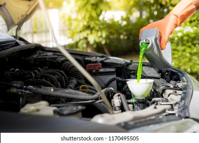 Close-up Male Hand With Gloves Filling Car Cooling System With Green Coolant.