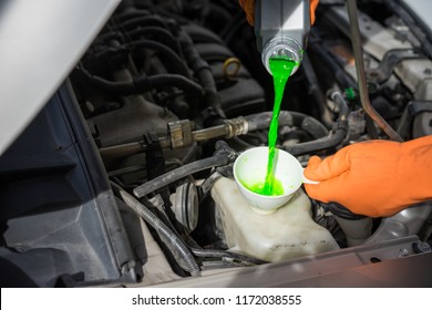 Close-up Male Hand With Gloves Filling Car Cooling System With Green Coolant.