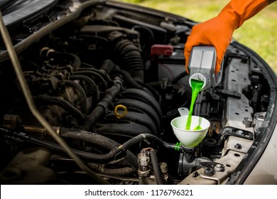 Close-up Male Hand With Gloves Filling Car Cooling System With Green Coolant.