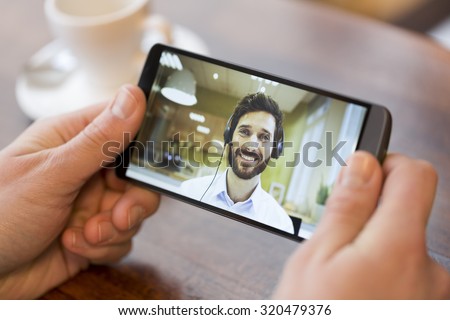 Closeup of a male hand holding his smart phone during a skype video