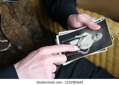 close-up male hand holding old vintage photos in sepia color 50s, 60s, carefully sorts out family values, concept of family tree, genealogy, memory of ancestors, family ties, childhood memories