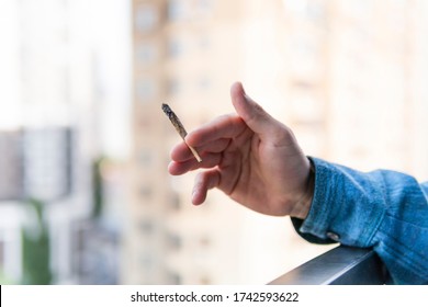 Cierre de la mano masculina sujetando y fumando juntas de marihuana o cigarrillos al aire libre. El cannabis es un concepto de medicina herbaria y alternativa