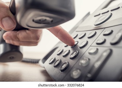 Closeup of male hand holding telephone receiver while dialing a telephone number to make a call using a black landline phone. With retro filter effect. - Shutterstock ID 332076824