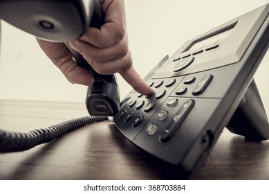 Closeup of male hand holding telephone receiver and dialing a phone number on a classical black landline telephone. Retro filter effect. - Shutterstock ID 368703884