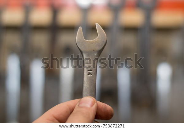 close-up of a male hand holding a wrench against a\
background of a tools